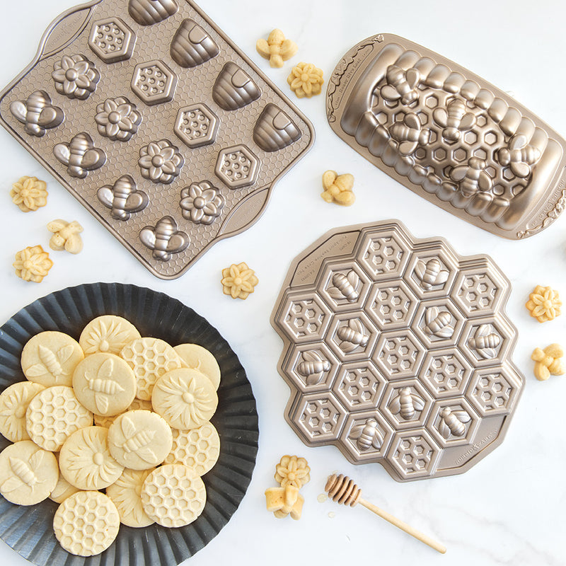 Nordic Ware Busy Bee Bitelet Pan with bee-shaped molds, surrounded by freshly baked cookies, perfect for crafting festive, bite-sized treats for special occasions.