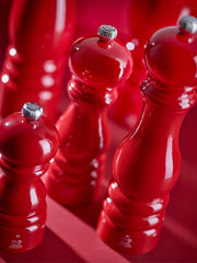 Peugeot | Paris Chef u'Select Passion Red Pepper Mill, 9 inches, with silver adjustment knob, classic hand-turned style, featured in a grouping against a red background.
