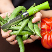 Hands holding green pea pods with an Opinel | N°7 First Opinel Folding Knife, Green, featuring a round-ended blade and Virobloc locking ring.