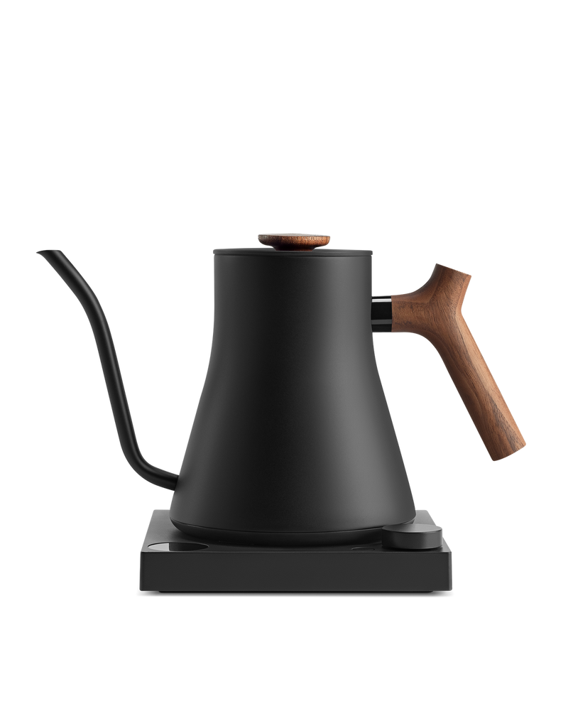 Fellow | Stagg EKG Pro Electric Kettle in matte black with walnut accents, featuring a precision pour spout, wooden handle, and variable temperature control on its power base.