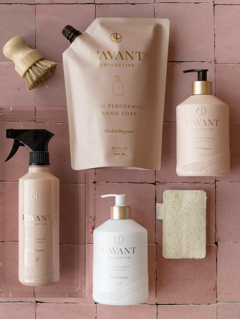 L'AVANT Collective High Performing Hand Soap - Blushed Bergamot, featuring elegant bottles and a wooden brush, ideal for a luxurious washing experience.