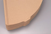 Stacked unassembled HARIO USA - V60 Paper Filters, showcasing the edge of die-cut cardboard pieces designed for optimal coffee brewing with V60 drippers.