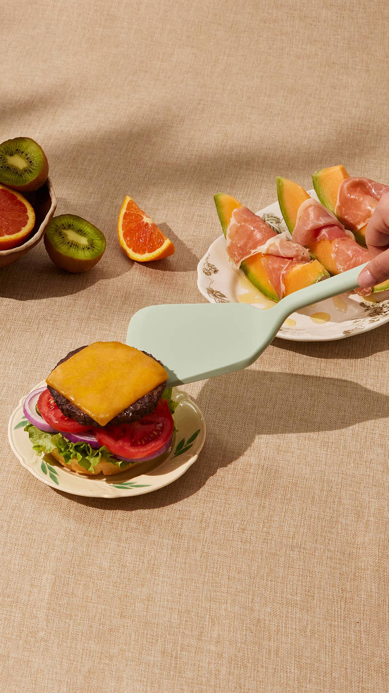 GIR Ultimate Turner: Sprinkles in use, expertly lifting a cheeseburger, showcasing its sturdy design ideal for handling hefty foods.