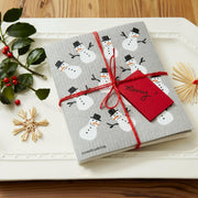 Three Bluebirds Swedish Dishcloths with whimsical holiday designs, including a straw snowflake and snowman, on a wood surface. Sustainable and stylish for kitchen chores.