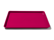 Great Jones | Holy Sheet - Pepper: A pink, half-sized sheet pan with nonstick ceramic coating, ideal for easy cleanup and stylish enough for table presentation.