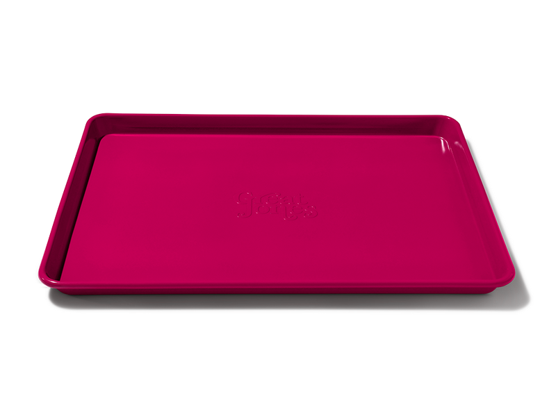 Great Jones | Holy Sheet - Pepper: A pink, half-sized sheet pan with nonstick ceramic coating, ideal for easy cleanup and stylish enough for table presentation.