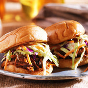 Two pulled-pork sliders topped with coleslaw, highlighting Southern Roots Sisters - Raspberry Chipotle Jam, perfect for adding a sweet, smoky twist.