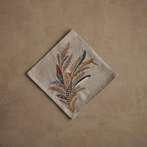 Coral & Tusk - Wheat Harvest Dinner Napkin features autumnal embroidery of feathers and grasses, set on natural linen, perfect for a bountiful fall table. Measures 20 × 20.