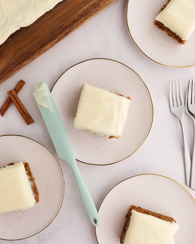 GIR | Ultimate Spreader - Sprinkles displayed with a white frosted cake slice on a plate, alongside a knife and fork, illustrating its versatile use in baking.