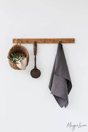 Linen tea towel hung on a hook, featuring a basket nearby, showcasing its functionality and elegance for kitchen use.