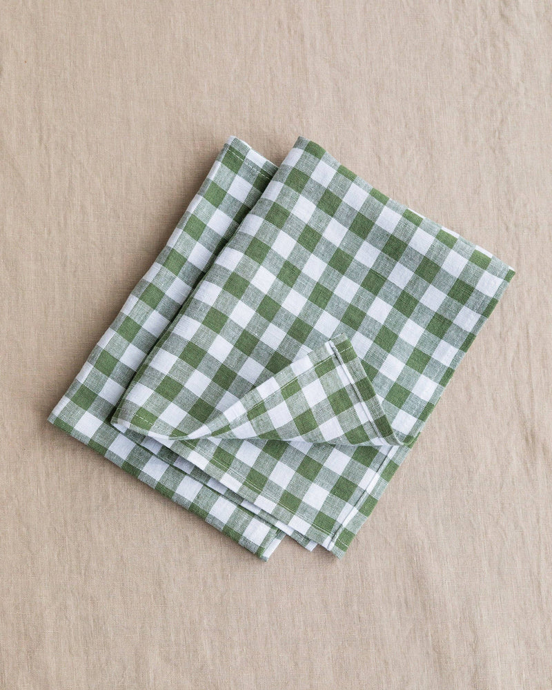 Forest green gingham linen placemat set of 2, neatly folded, showcasing checkered pattern, ideal for stylish dining.