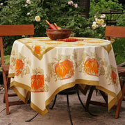 Caravan Home - Pumpkin Orange & Mustard Tablecloth: 71 x 71, handprinted with pumpkins, adorns a garden table, embodying autumnal charm and artisanal craftsmanship.