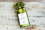 Schermer Pecans - GLAZED PECANS: A green bag of Georgia pecans on wood, ideal for charcuterie boards, ice cream toppings, or bar cart snacks.