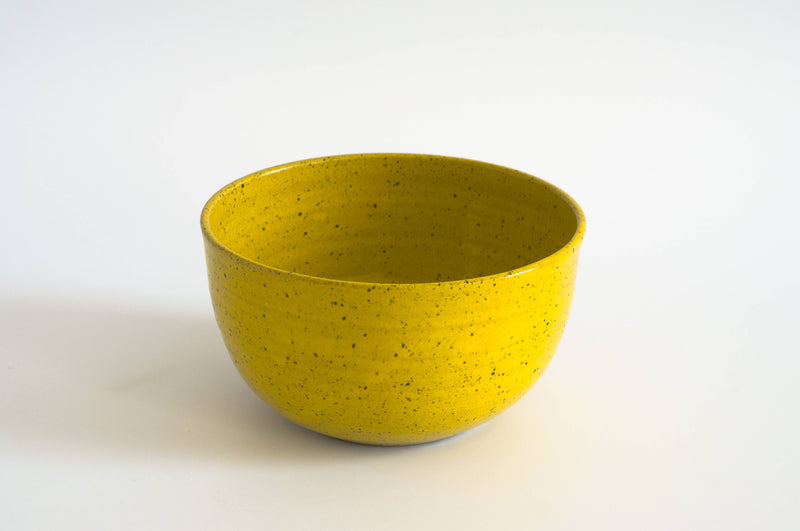 RachaelPots - Laura Bowl: Coral, a tall, ribbed, speckled yellow ceramic bowl, ideal for diverse meals, handcrafted in Brooklyn, set against a white background.