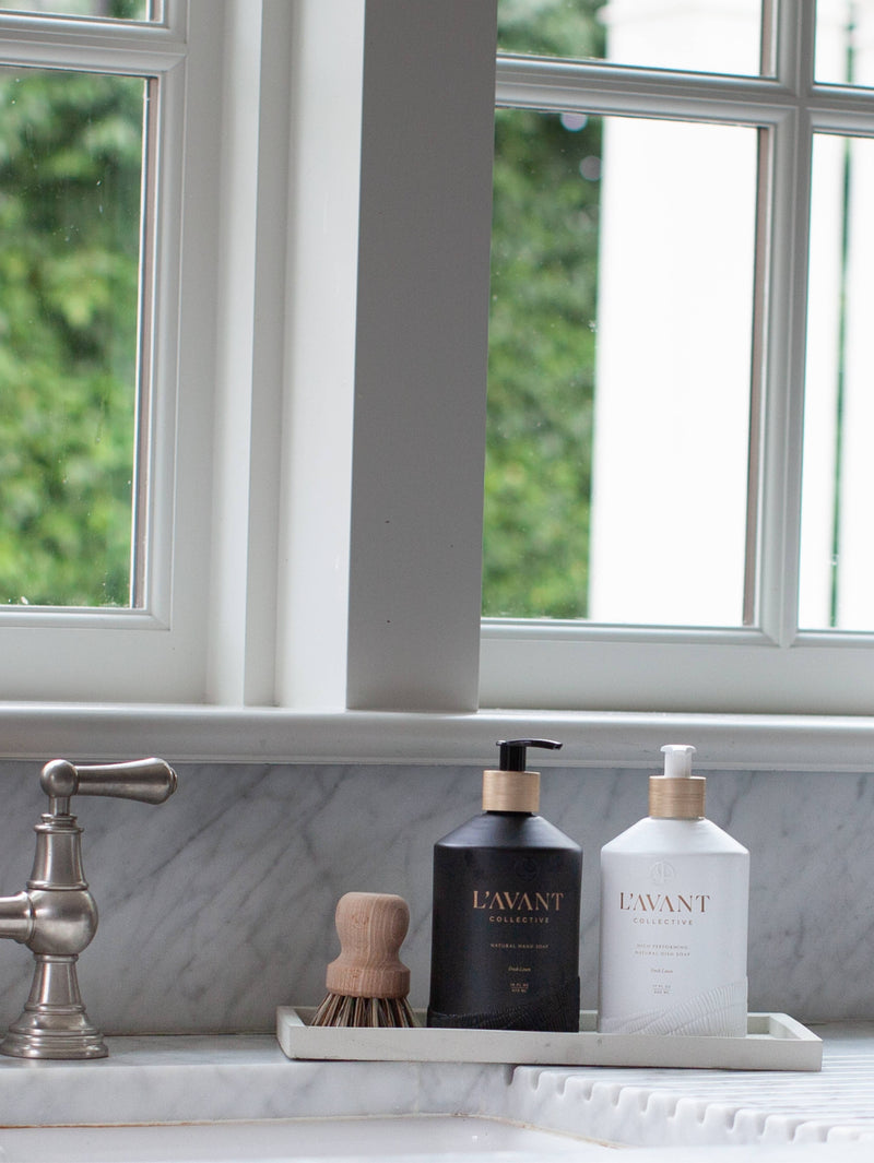 L'AVANT Collective - Fresh Linen Hand Soap in a matte black glass bottle, elegantly displayed on a bathroom counter next to a white bottle.
