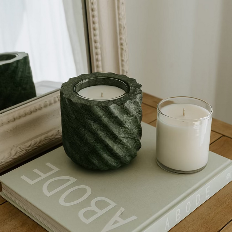 Emerald Green Marble Refillable Candle in textured vessel on book, showcasing unique marble design, alongside a clear glass candle, styled on a wooden surface.