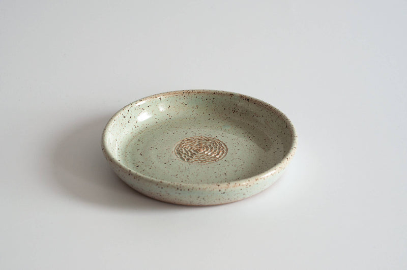 RachaelPots - Garlic Scraper: Nude/White, a mint-green ceramic dish with concentric rings, ideal for pureeing garlic, ginger, or onions. Handcrafted, lead-free, microwave and dishwasher safe.