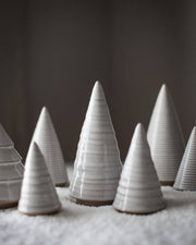 Farmhouse Pottery - Spruce Woodland Trees: Petite, small white-glazed ceramic cones on a textured surface, showcasing varying heights for elegant, nature-inspired decor.