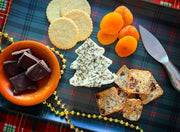 Tulip Tree Creamery - Nettle cheese shaped like a Christmas tree on a tartan cloth, surrounded by crackers, dried apricots, crispbreads, dark chocolate, and a cheese knife.