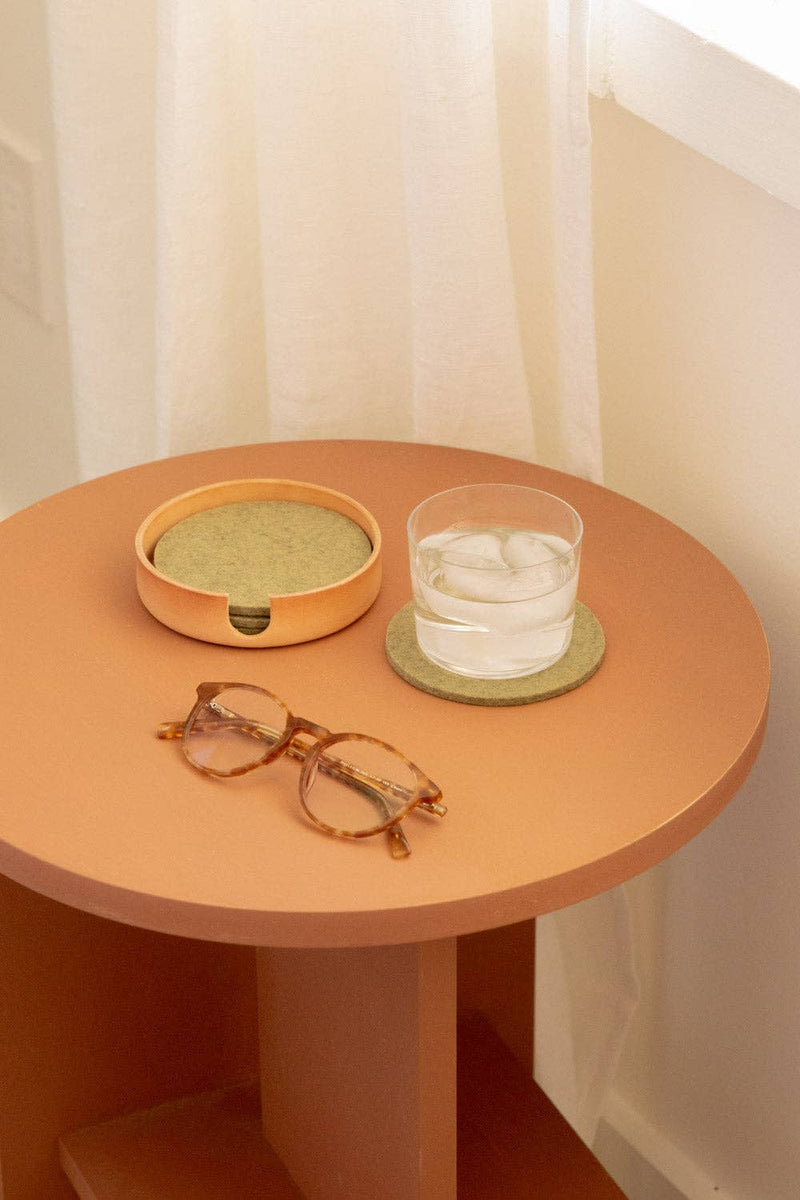 Graf Lantz - Bierfilzl Merino Wool Felt Round Coaster Solid 4 Pack: Sage on a table with a glass of water and an ashtray.