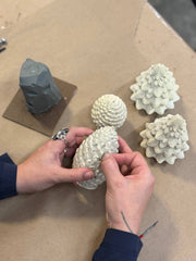 Mo&Co Home Exclusive: Sculpted Beeswax Pine Cones being hand-refined in a studio, showcasing detailed craftsmanship and artistry for elegant holiday decor. Available in two sizes.