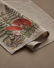 Coral & Tusk - Mushrooms and Ferns Bouquet Dinner Napkin features embroidered ferns and mushrooms on natural linen, ideal for a whimsical table setting. Measures 20 × 20.