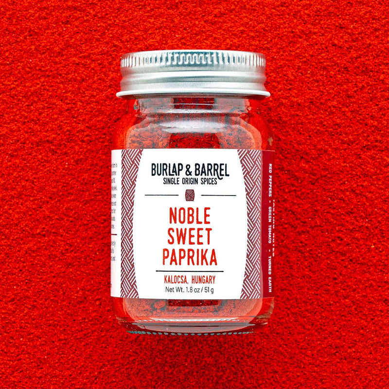 Burlap & Barrel - Noble Sweet Paprika - Single Origin Spice & Seasoning: 1.8 oz glass jar on paprika-covered surface, showcasing vibrant Hungarian spice from Kalocsa.