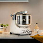 Ankarsrum stand mixer in a cozy kitchen setting, paired with greenery, coffee syrup, and a pastry, exemplifying Athens Cooks' curated kitchen elegance.