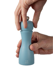 Hands opening a Peugeot | Tahiti Duo Salt + Pepper Mills, Air, showcasing its hourglass design, suitable for refilling, embodying elegance and functionality for any kitchen setting.