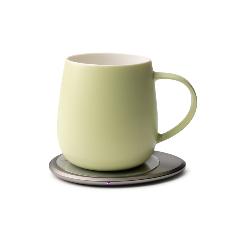 OHOM - Ui 3 Self-heating Mug Set: Jasmine White on an electric coaster, keeping beverages warm and wirelessly charging phones, ideal for kitchen enthusiasts.