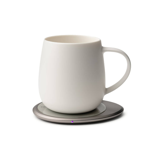 OHOM - Ui 3 Self-heating Mug Set: Jasmine White shown on an electric coaster, keeping beverages warm, with wireless phone charging capability.
