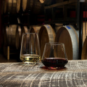 Zwiesel Fortessa | Pure Stemless Wine Tumbler, 18.5 oz, set on a wooden barrel, showcasing elegant design and postmodern aesthetics in a winery setting.