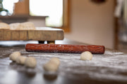 Close-up of Earlywood Dumpling Pin - Jatoba on a table, ideal for rolling dumplings and more, showcasing its smooth, durable wooden craftsmanship.