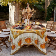 Caravan Home's Pumpkin Orange & Mustard Tablecloth on a round table, features a pumpkin motif, enhancing an outdoor autumn dining setup with artisanal elegance.