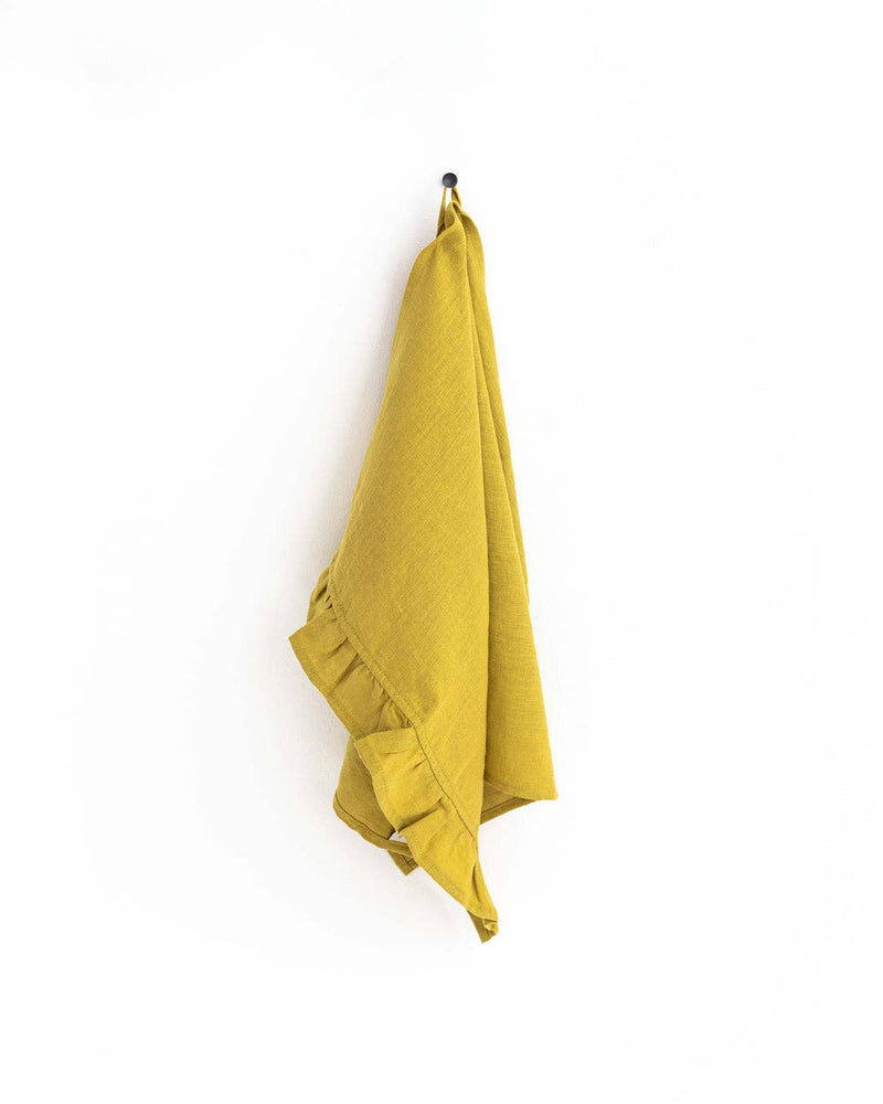 MagicLinen ruffle trim tea towel hanging on a hook, showcasing its soft linen texture and practical loop for easy kitchen use.
