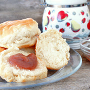 Southern Roots Sisters - Apple Butter spread on a biscuit, with a glass bowl of the spread and a decorative jar in a rustic breakfast setup.