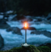 VANMOKUM | GRAYPANTS Wick Portable Rechargeable Lamp - Black, shown outdoors on a rock, combines candle ambiance with flashlight utility for versatile, shared lighting experiences.