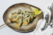 Plate of cubed avocado with creamy dressing, raw onion, black sesame seeds, and lime wedges. Showcasing Villa Jerada - Nigella - 90g from Athens Cooks.
