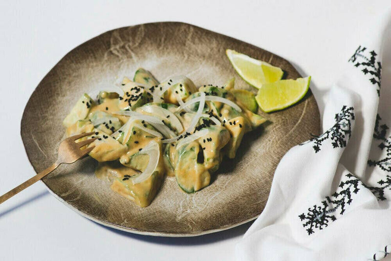 Plate of cubed avocado with creamy dressing, raw onion, black sesame seeds, and lime wedges. Showcasing Villa Jerada - Nigella - 90g from Athens Cooks.