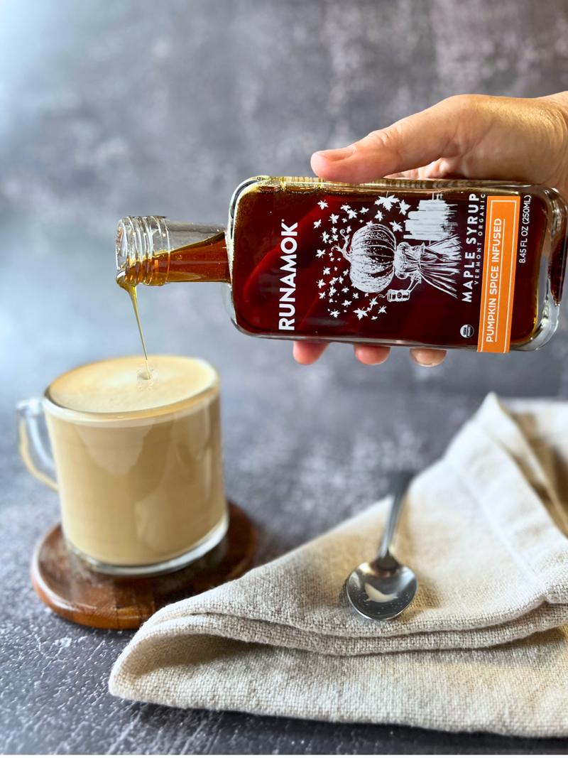 Runamok - Pumpkin Spice Infused Organic Maple Syrup being poured into a foamy latte in a cozy setting, highlighting its autumn-inspired flavors.