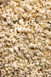Poppy Hand-Crafted Popcorn - Dill Pickle Popcorn, a crunchy snack featuring white cheddar, vinegar, and dill, showcased in a pile. Perfect for culinary enthusiasts.