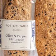 Potters Table - Cured Olive & Cracked Pepper Flatbreads, hand-stretched, featuring black pepper and olive bits, ideal for enhancing cheese spreads or charcuterie boards.