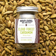 Burlap & Barrel - Cloud Forest Cardamom - Single Origin Spice & Seasoning: 1.7 oz glass jar of whole cardamom pods from Alta Verapaz, Guatemala, resting on more pods.