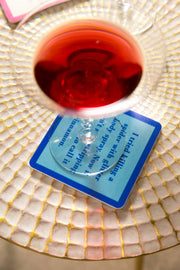 Drinks on Me - COASTER Powerful Woman, featuring a deep-red cocktail in a coupe glass on a witty blue coaster, enhancing home bar decor with humor.