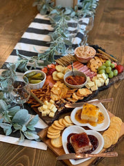 Charcuterie spread featuring Southern Roots Sisters - Blackberry Pepper Jam in a heart-shaped dish, surrounded by cheeses, crackers, cured meats, fruits, and nuts.