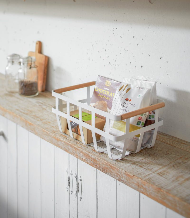 Yamazaki Home | Steel + Wood Storage Baskets, Large, displayed in a light-filled kitchen, organizing packaged foods on a rustic countertop with glass jar and cutting board nearby.