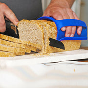Hand using WOW GEAR | Gripmitt - Green to safely slice bread, showcasing its versatile use in handling hot and cold kitchen tasks.