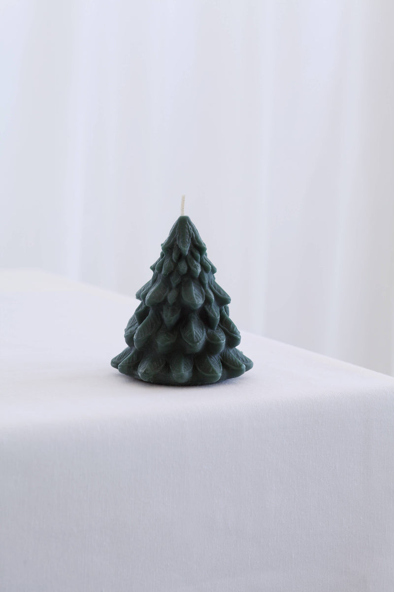 Mo&Co Home Exclusive: Small green beeswax candle sculpted as a pine tree, unlit, showcasing intricate design inspired by vintage ornaments and holiday nostalgia.