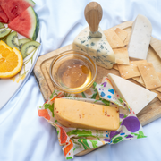 Bee's Wrap - New! Garden Party - Assorted 3 Pack, showcasing reusable wraps with cheese and fruit, ideal for preserving freshness and flavor.