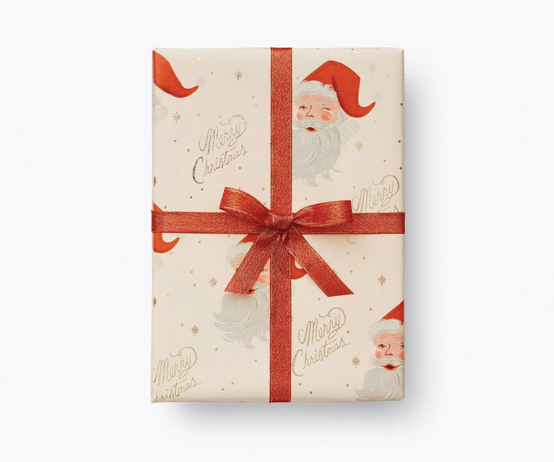 Rifle Paper Co. - Santa Continuous Wrapping Roll featuring vintage Santa design with Merry Christmas text, red ribbon, and gold foil accents, ideal for festive gifting.